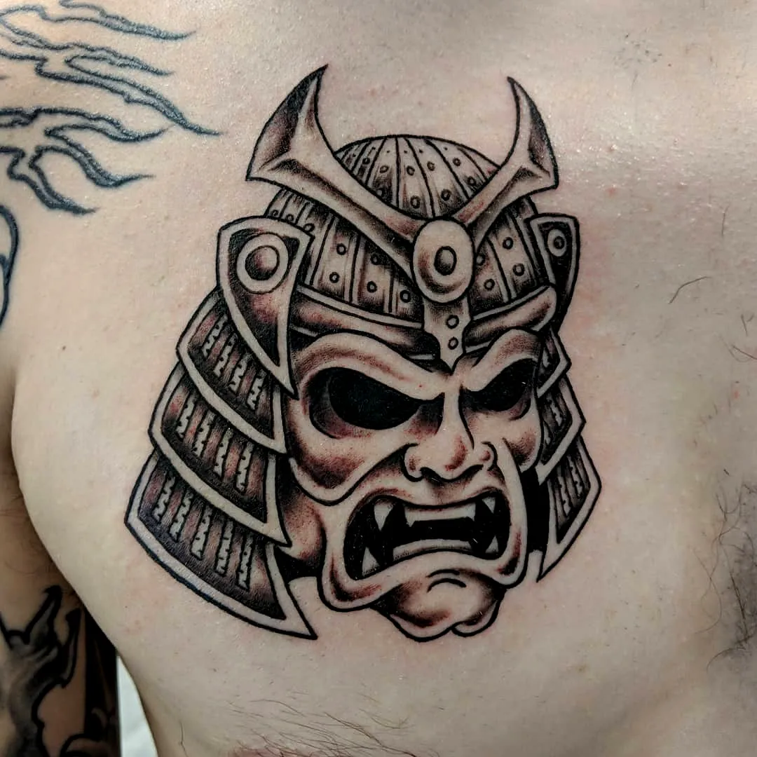 Fierce samurai mask arm tattoo in black and gray shading