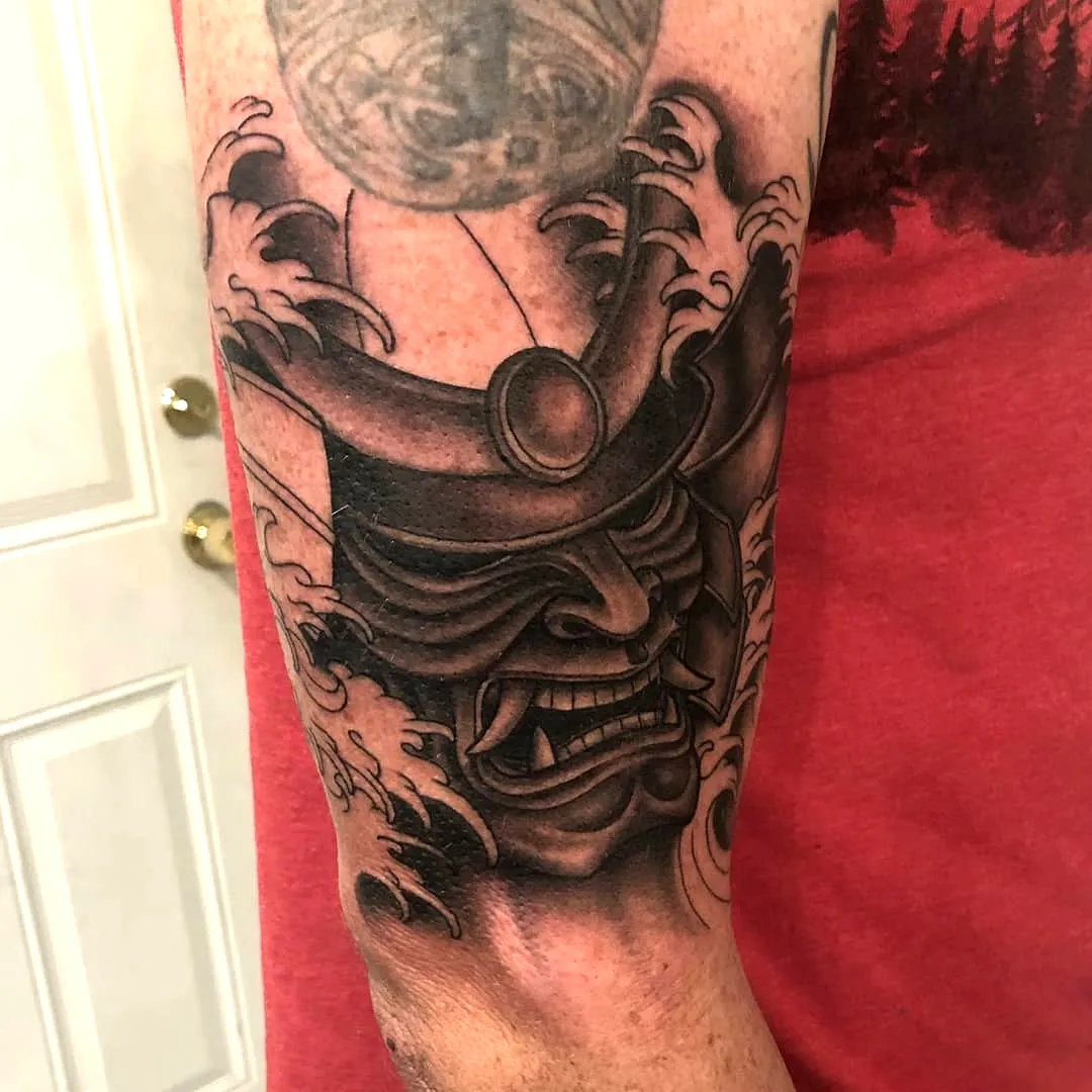 Fierce Samurai Mask Forearm Tattoo with Swirling Waves in Black and Grey