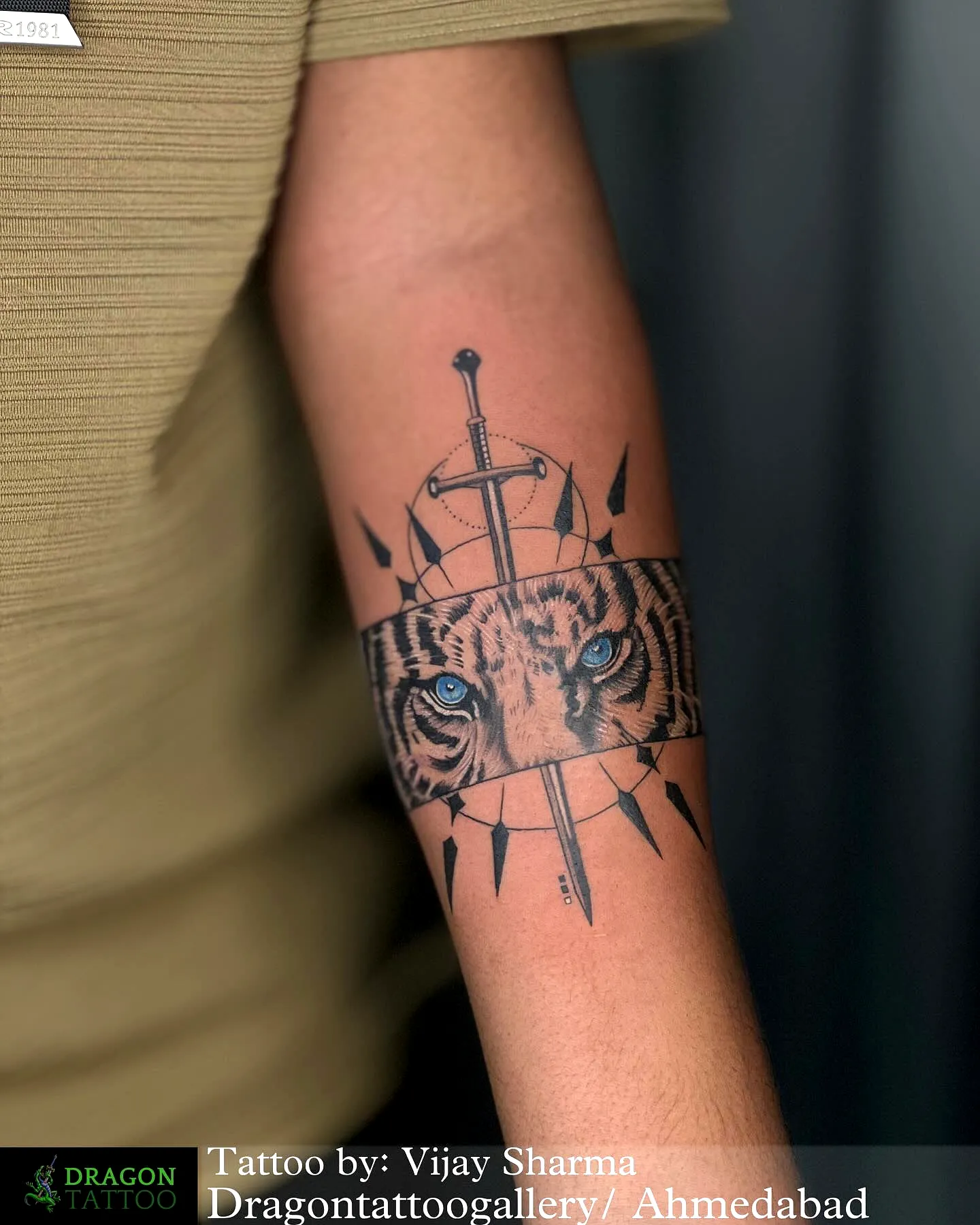 Fierce tiger eye forearm tattoo featuring blue accents and decorative band elements