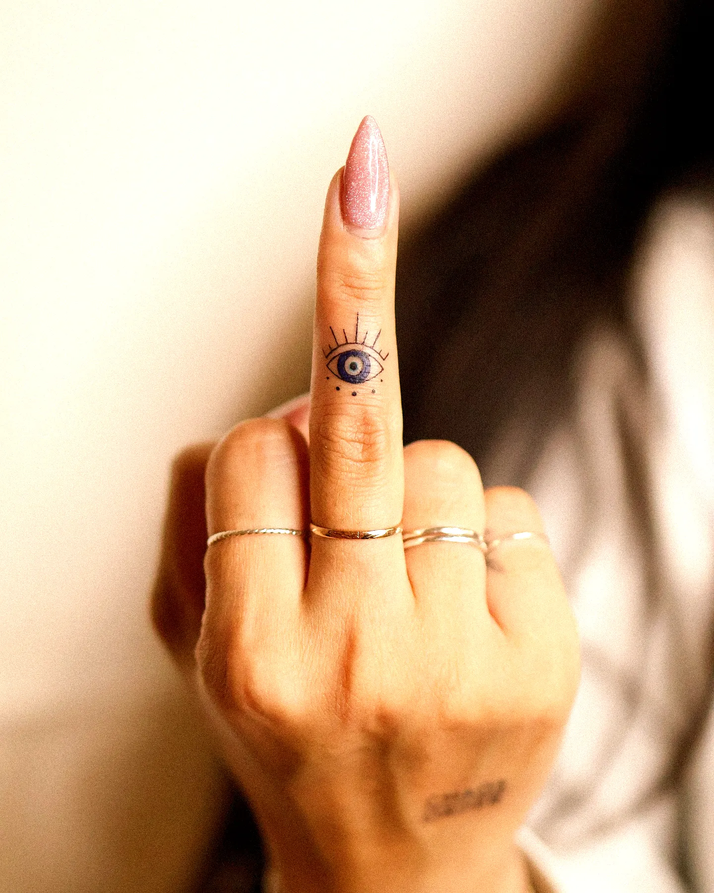 Finger tattoo for women featuring an eye design with rays and black ink