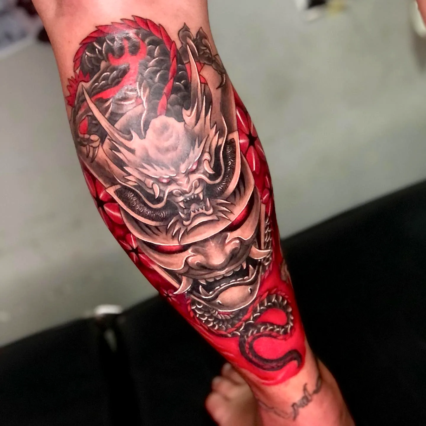 Intricate Samura mask tattoo with dragon and demonic face on calf