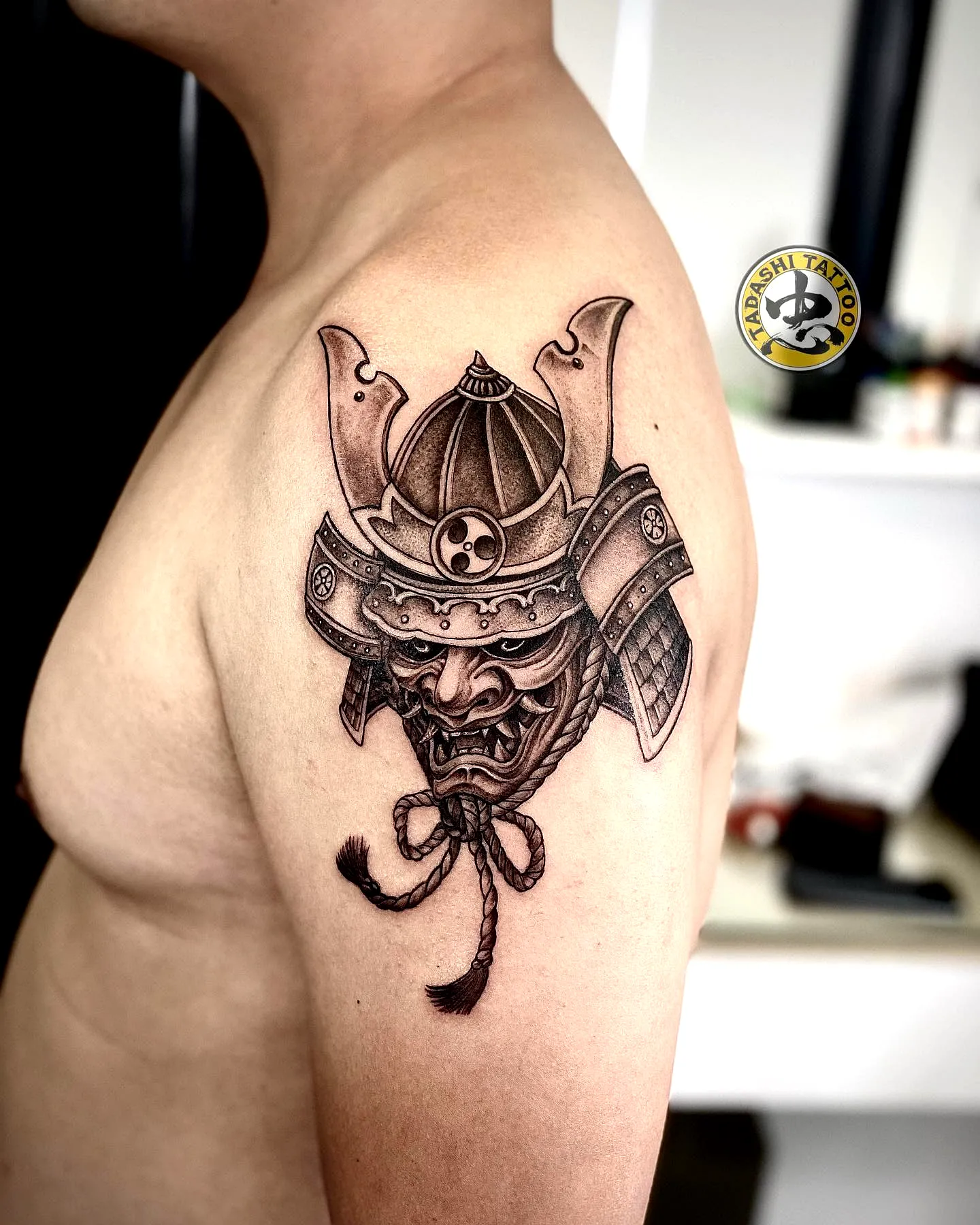 Intricate Samurai Mask Tattoo on Upper Arm in Black and Gray