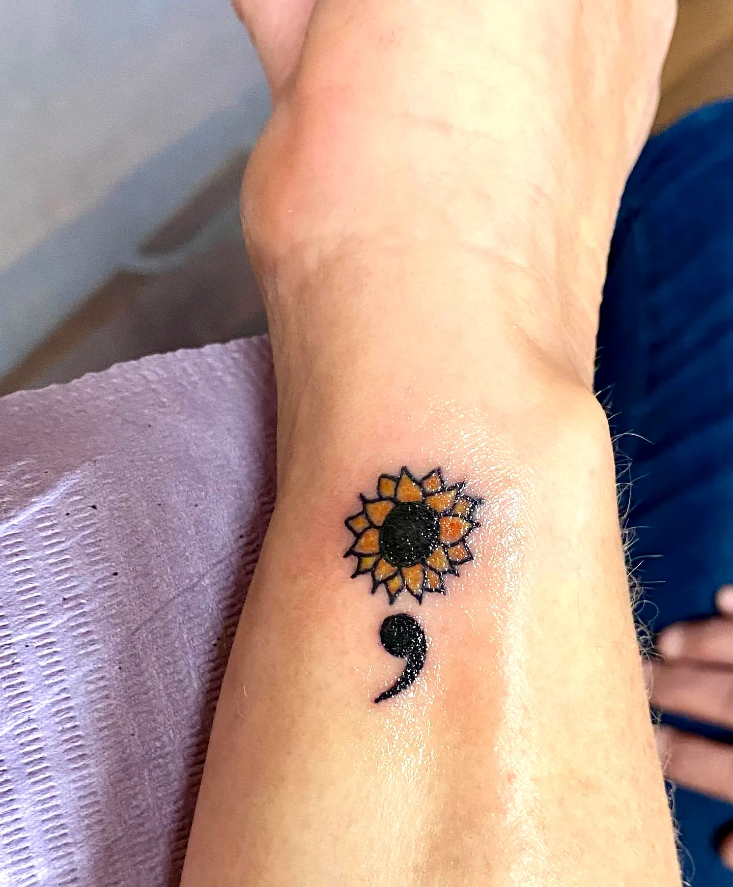 Vibrant sunflower and black semicolon wrist tattoo