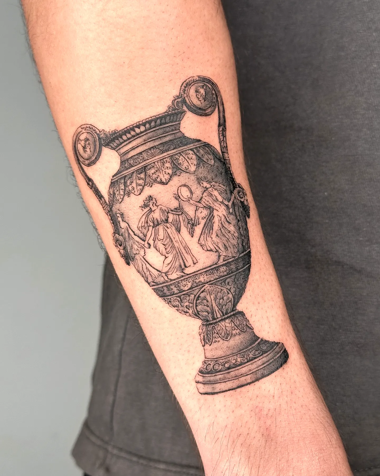 Greek urn forearm tattoo in black and gray