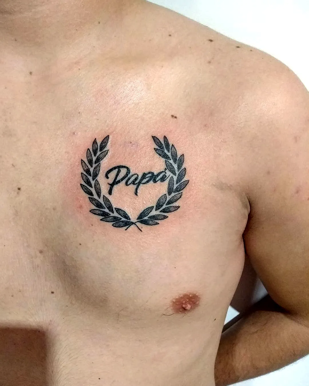 Laurel Wreath Chest Tattoo in Black Ink