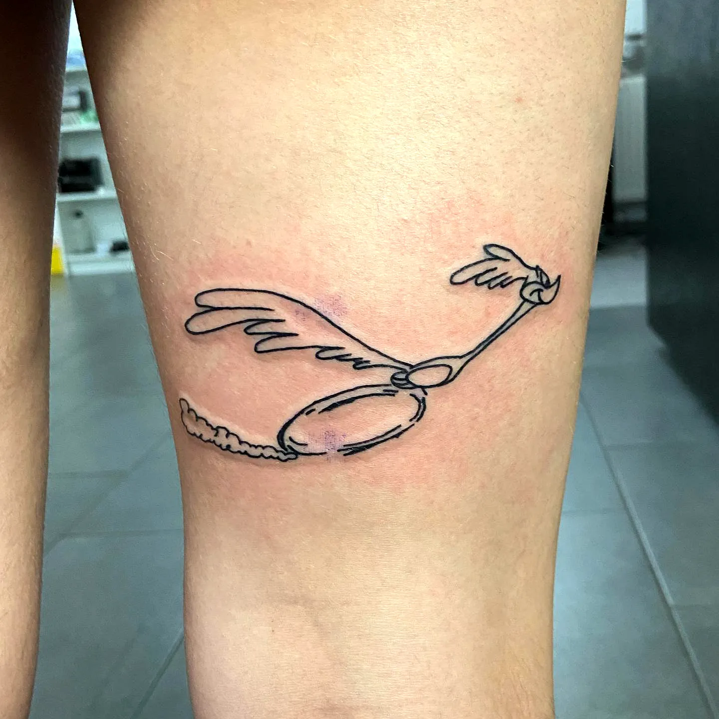 Minimalist Winged Object Thigh Tattoo