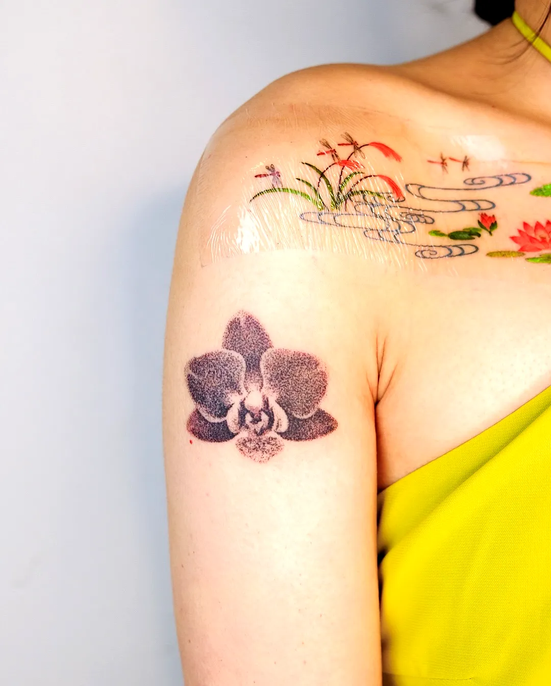 Orchid Upper Arm Tattoo with Floral Waves