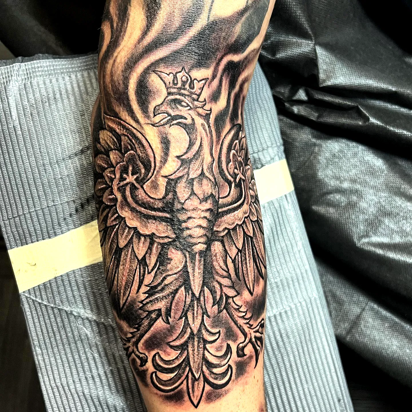 Phoenix forearm tattoo in black and gray