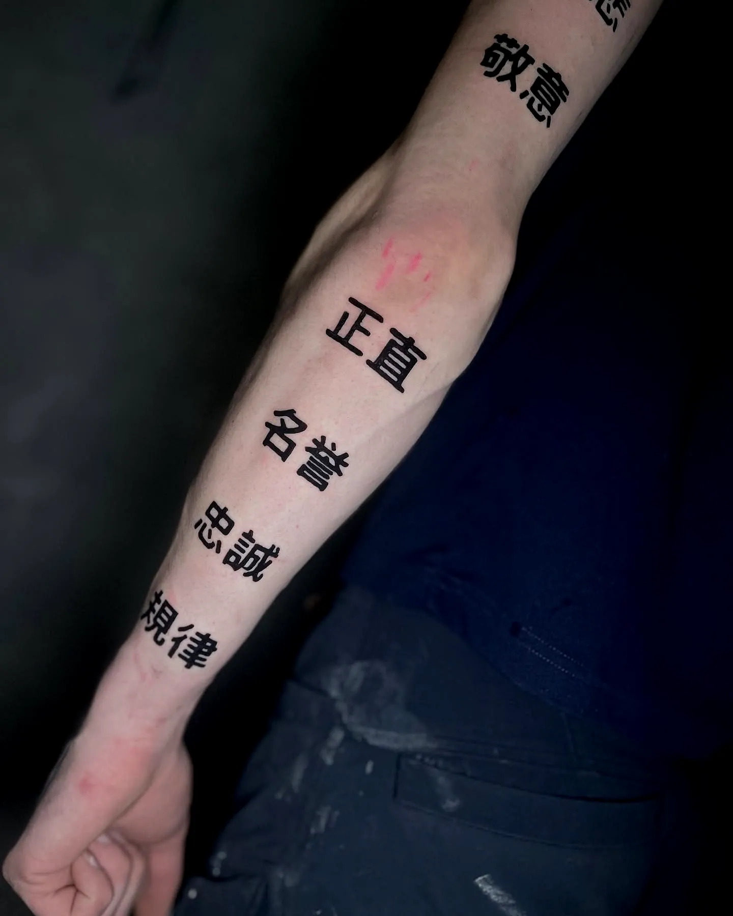 Stylized Black Text Forearm Tattoo