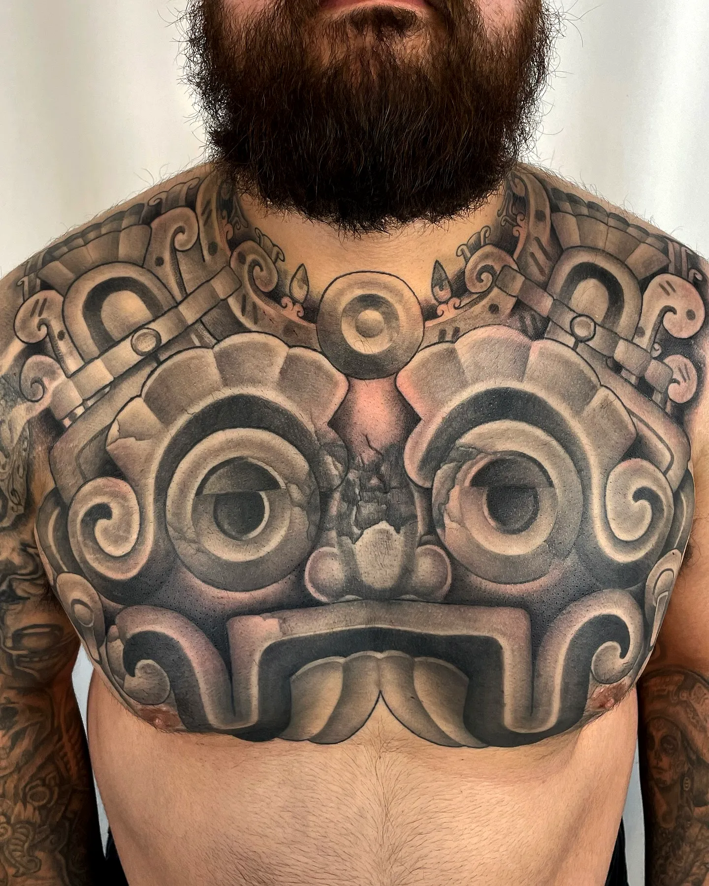Stylized Face Chest Tattoo in Black Grayscale