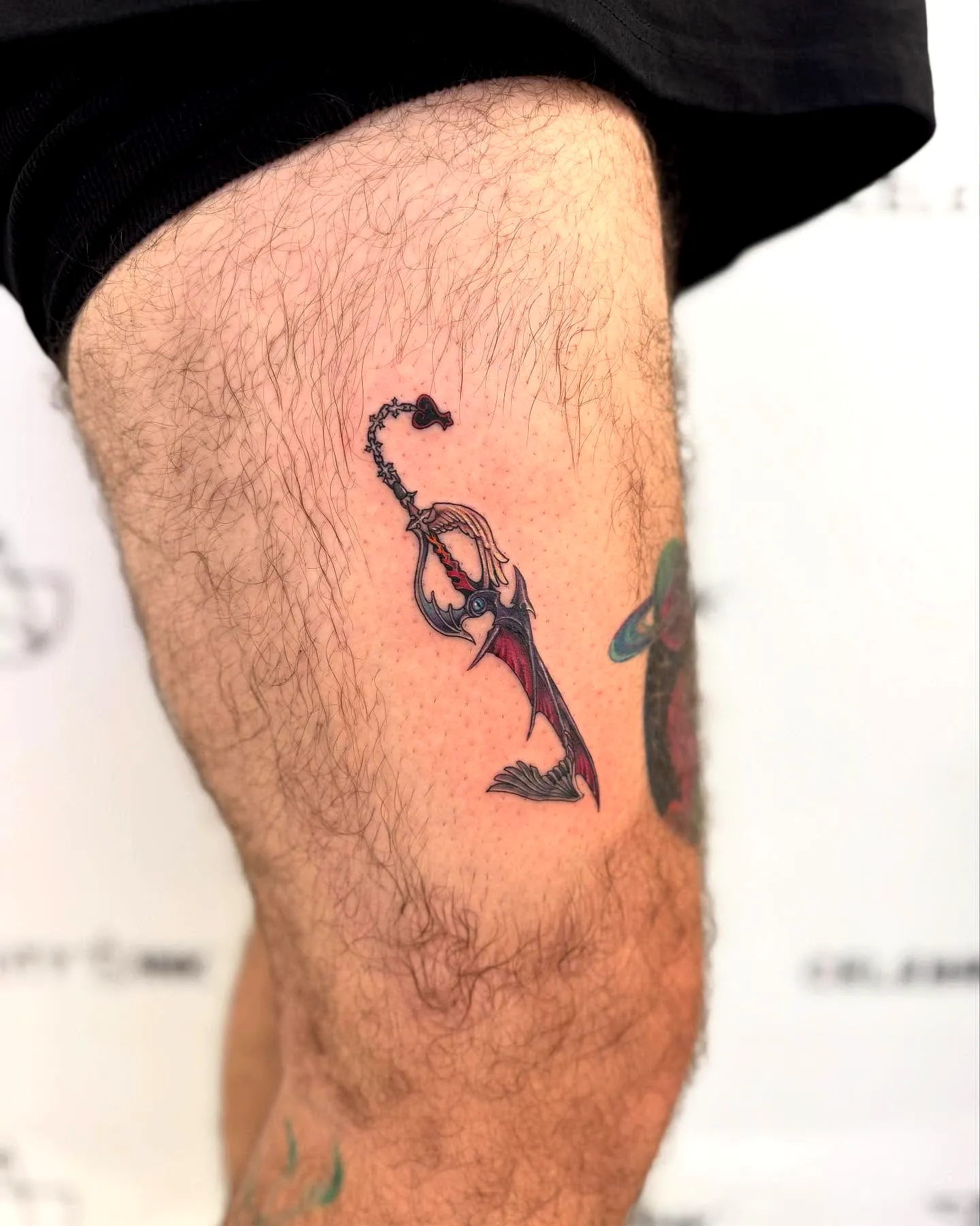 Stylized Fishing Hook Thigh Tattoo