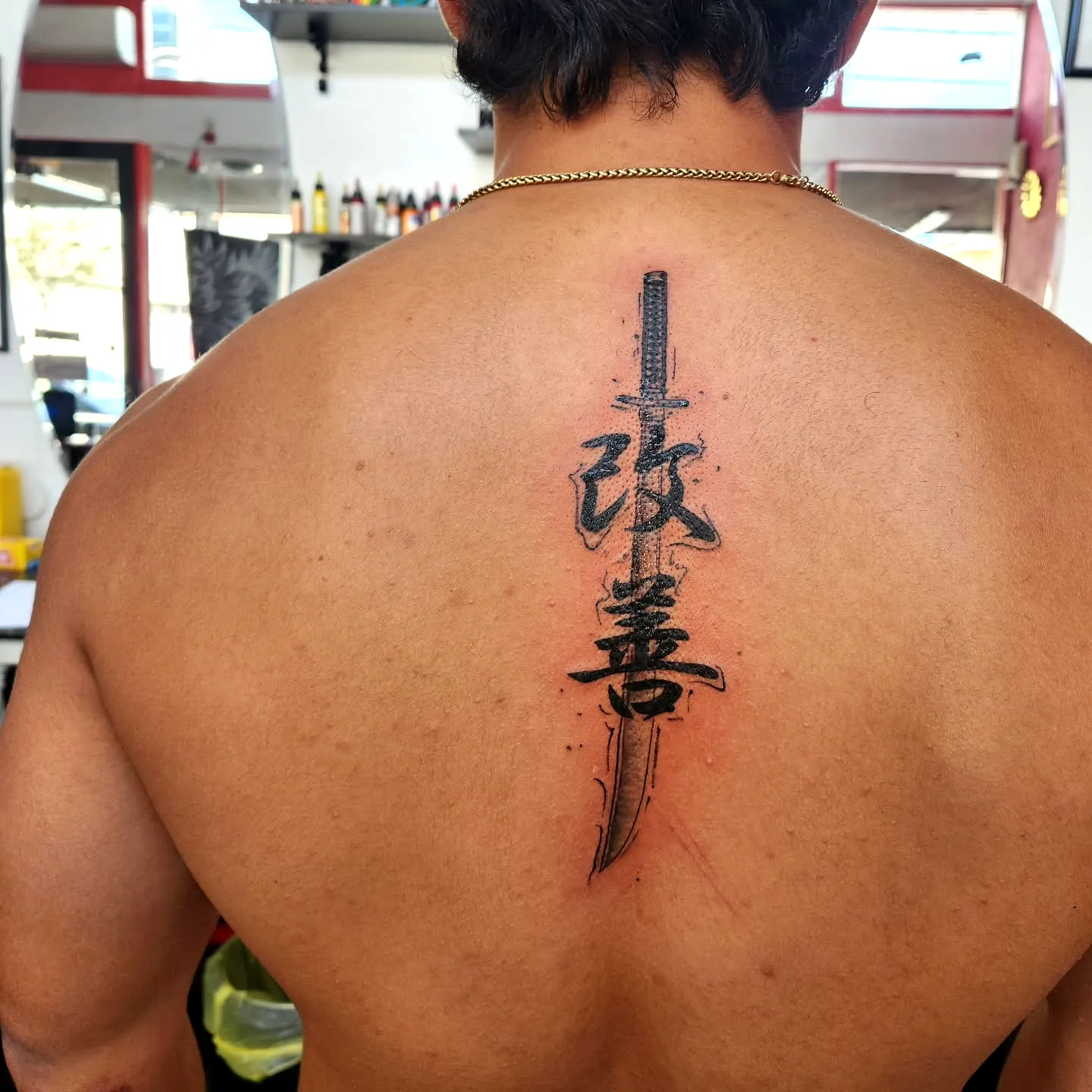 Stylized Sword Upper Back Tattoo