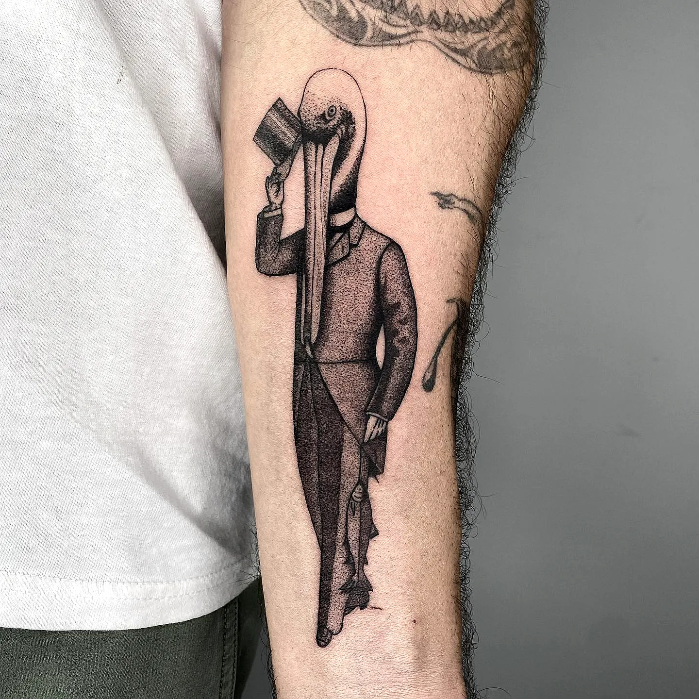 Surreal Bird-Head Forearm Tattoo