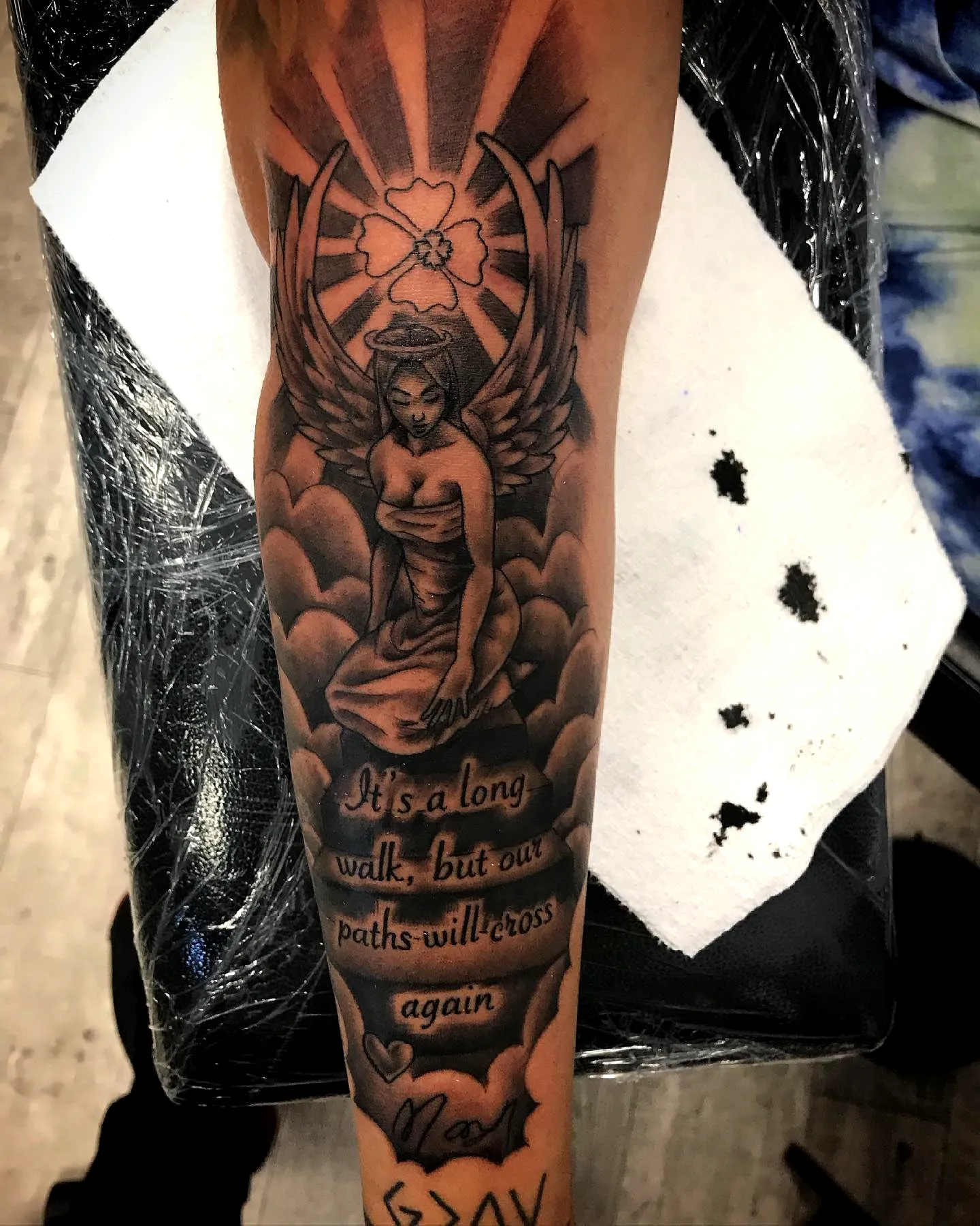 Winged figure arm tattoo with quote